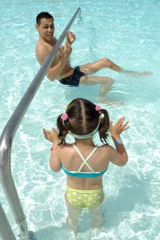 Father and daughter are playing in pool.