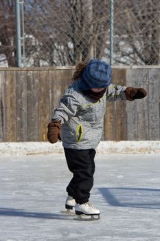 Little girl skating at an outdoor skating rink.