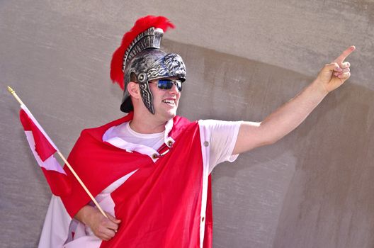Youn man in his 20s celebrating Canada Day with a flag and gladiator costume.