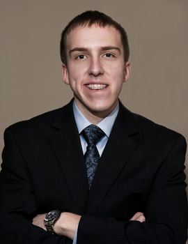 Young business man with braces standing with arms folded.