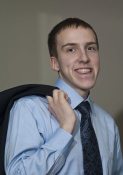 Young business man with braces standing holding suit coat over shoulder.