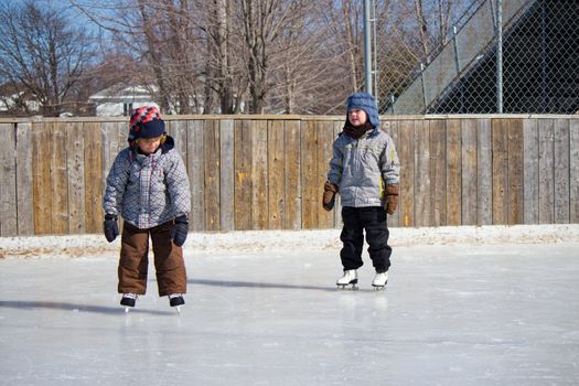 Children playing and skating at the outdoor skating rink during winter.