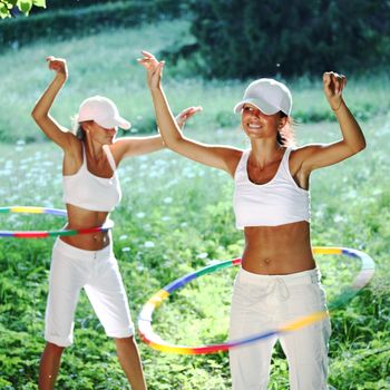 woman rotates hula hoop on nature background