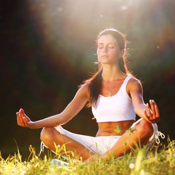 yoga woman on green grass lotus pose in sunrise light