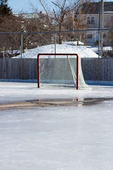 Ice hockey rink with hockey net on melting ice in the early spring.