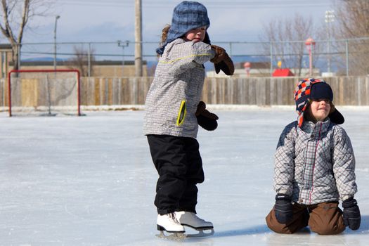 Children playing and skating at the outdoor skating rink during winter.