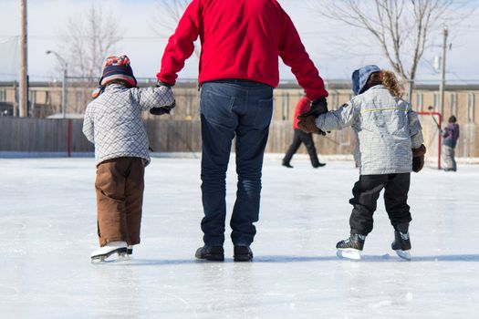 Family having fun at the outdoor skating rink in winter.