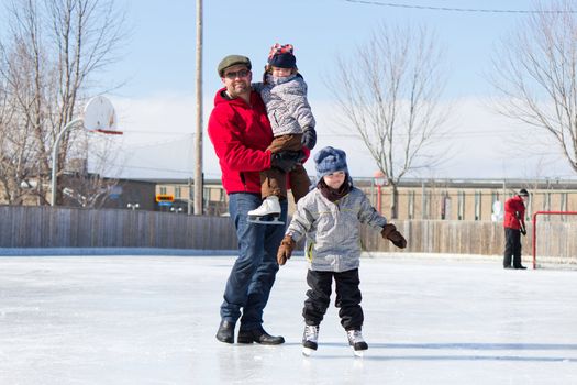 Father with son and daughter playing at the skating rink in winter.