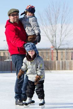 Father with son and daughter playing at the skating rink in winter.