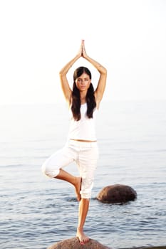 Young woman practicing yoga  near the ocean