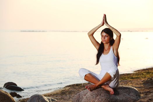 Young woman practicing yoga  near the ocean