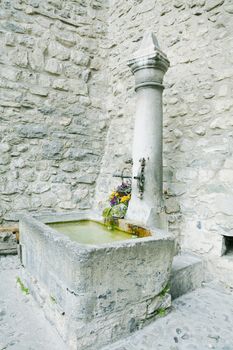 old stone fountain with watering in Chateau Chiilon, Montreux, Switzerland