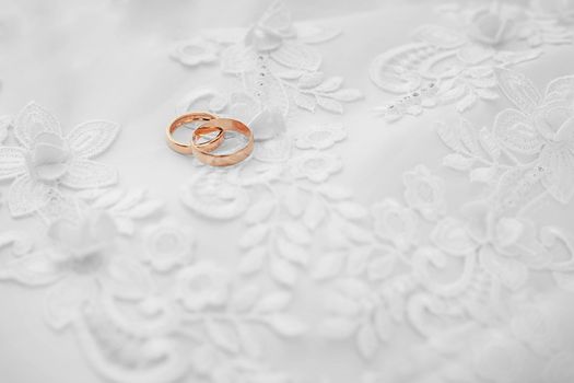 Two gold wedding rings on white dress background
