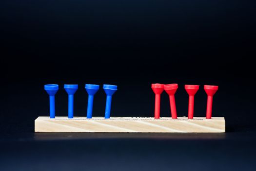 Blue and red golf tees on a black background in a line with some leaning.