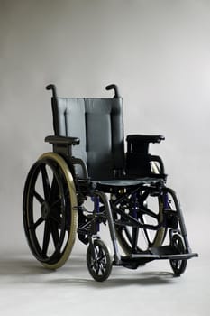 Touching studio shot of empty wheelchair over grey background, perfect for healthcare or other medical use.