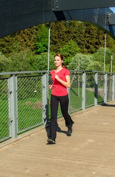 Young attractive woman jogging on the bridge