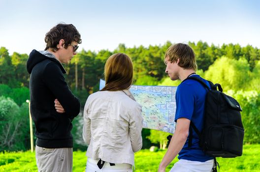 Three friends traveling, they look at a map