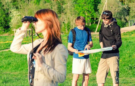 Three friends traveling. Girl looking through binoculars