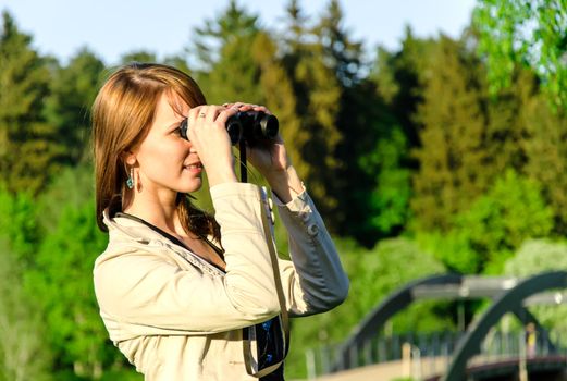 Attractive young woman looking through binoculars