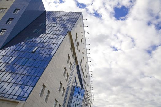 windows of skyscraper with reflections on a background cloudy sky