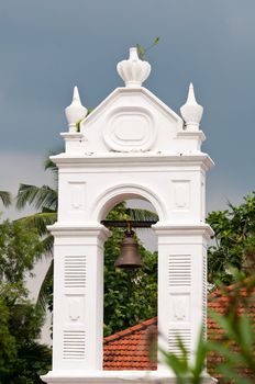 Old church bell in white arch as example of colonial architecture