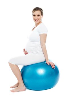 Pregnant lady sitting on exercise ball holding her belly