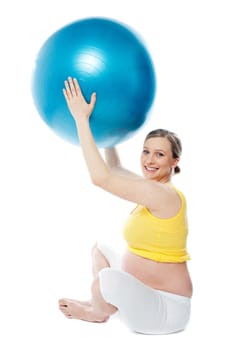 Smiling pregnant woman with a ball in studio. Isolated