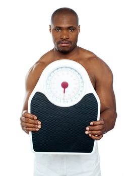 Attractive athlete showing weighing scale against white background