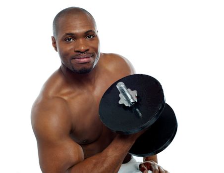 Powerful muscular young man lifting weights. Smiling at camera