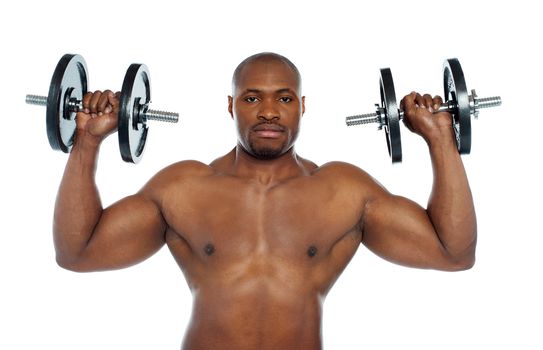 Shirtless african male holding dumbbells over his shoulders. Exercising
