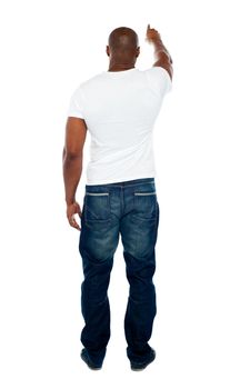 Rear view of strong young man pointing at copyspace isolated against white background