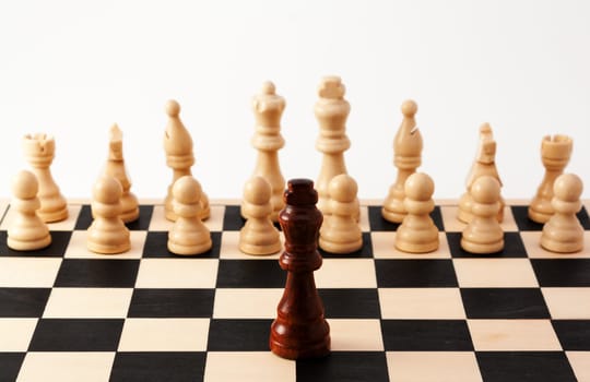 Image of a single black piece standing in front of bunch of white pieces, Can be used for racism, diversity, challenge, courage, adversity, or many other uses.