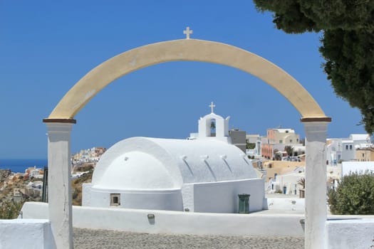 Small arch upon a chapel and view on Oia village behind, Santorini, Greece