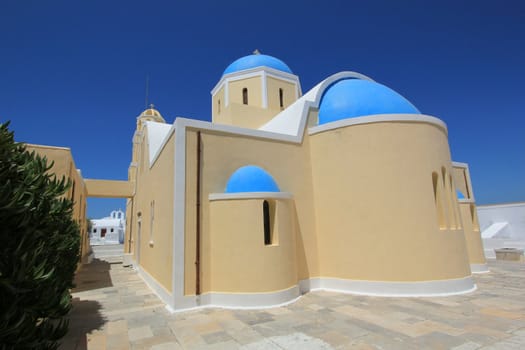 Blue dome and yellow walls of a greek orthodox church in Santorini island, Greece, by beautiful weather