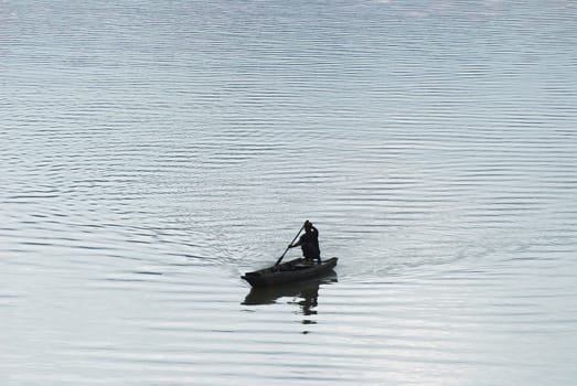 a local fishman row a boat in a big resevoir from Thailand