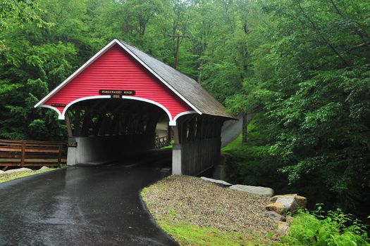 a red cover bridge in a green forest from New hamshire