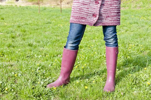 detail of woman wearing rubber boots on spring meadow