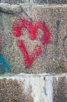 Red heart painted on ancient stone block wall background.