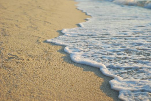 A foam-like wave on sand beach in a morning