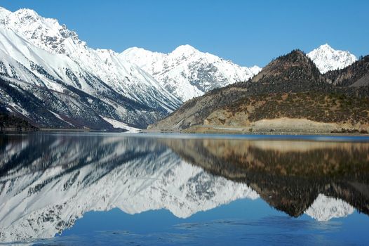 Landscape of snow-capped mountains with a mirror in the lake