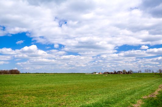 beautiful Dutch plain landscape with farm house and blue sky and white clouds