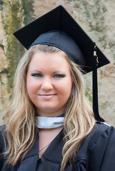 Portrait of a female college graduate on graduation day. She is wearing a graduation cap and gown.