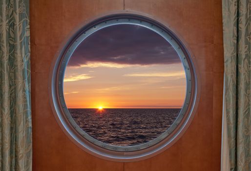 View of a sunrise through the porthole of a cruise ship.