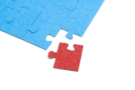 Blue Puzzle with one red jigsaw piece isolated on white background