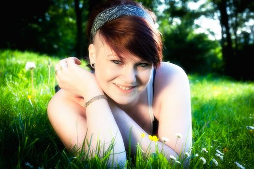 A beautiful young girl lying on the grass on a background of green 