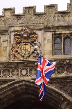 A union jack flag set against a royal crest. Crest adorns the entrance to Salisbury Cathedral - the cathedral gate.