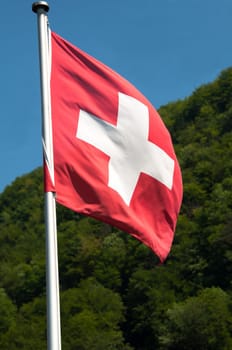View of Switzerland countryside - swiss flag with green mountains in the background