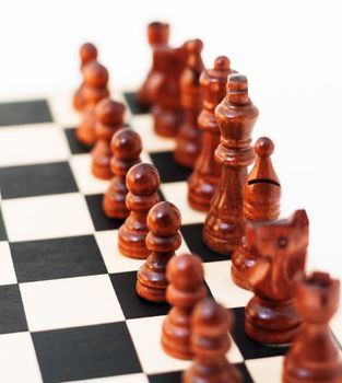 Black chess pieces made out of a red wood. Focus is shallow and places on the king piece