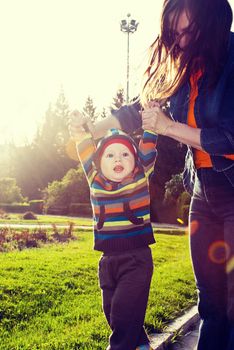 Happy young beautiful mother and her son have a walk in the park.