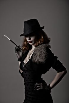 Retro shot of gangster woman in fedora hat and evening dress holding mouthpiece 